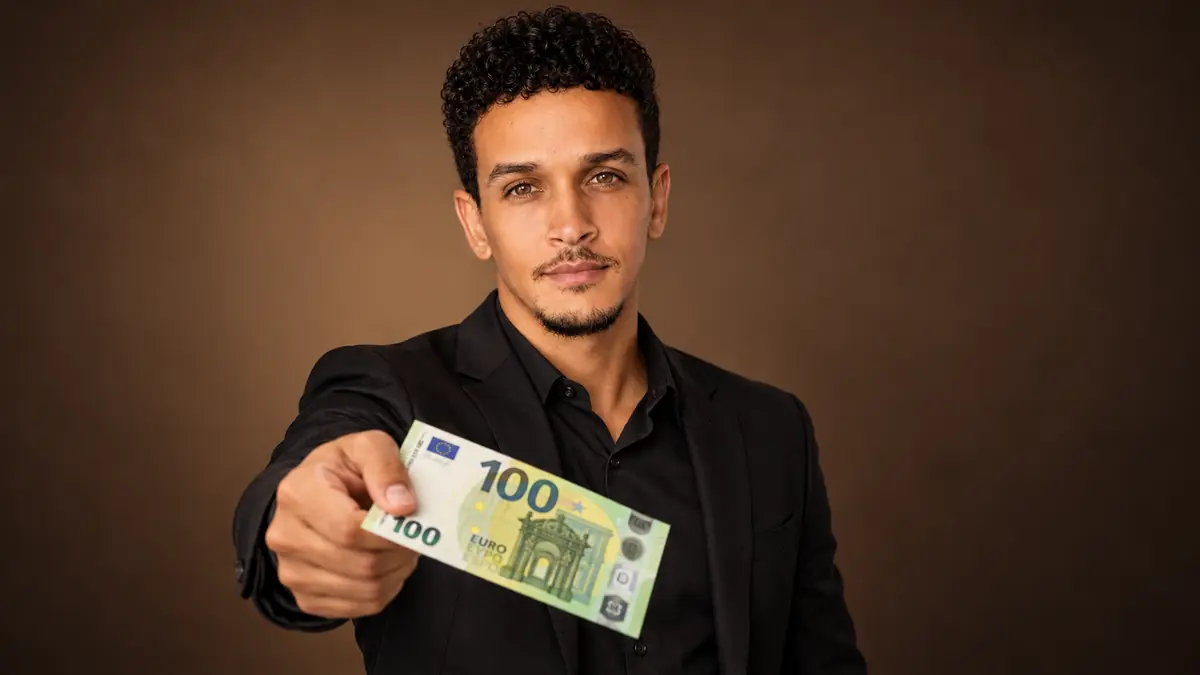 O mentor do programa segurando uma nota de 100 euros